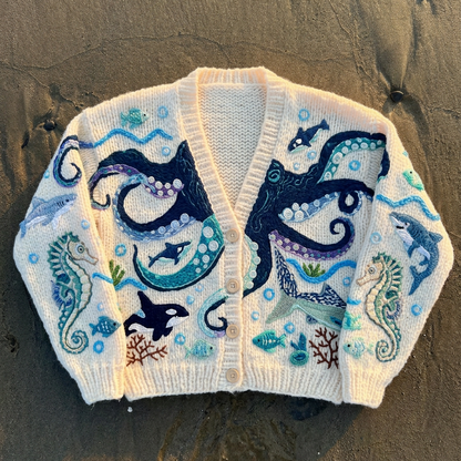 Children's sweater with ocean-themed design on a sandy surface